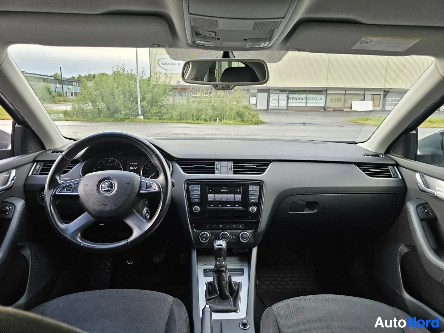 Ohjaamo: Skoda-merkkisen auton ohjaamo edestä katsottuna. Näkyvät mustavalkoinen monikäyttöinen ohjauspyörä, digitaalinen mittaristo, keskikonsoli ilmastoinnin ja radion