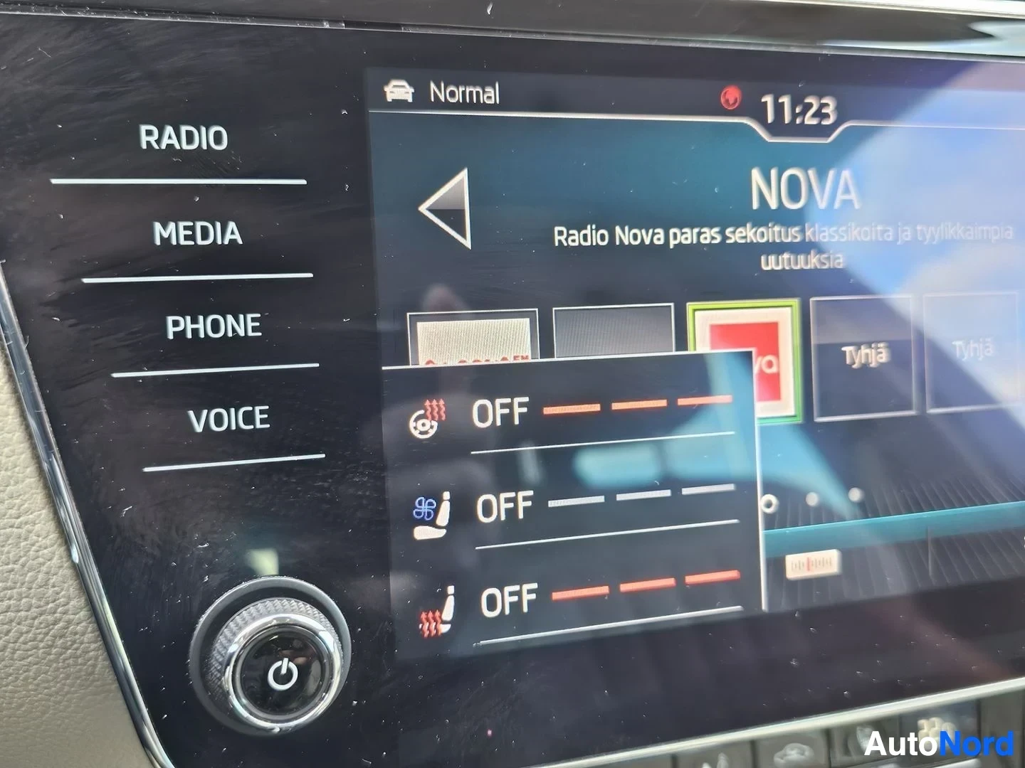 Yksityiskohta: Infotainment-näyttö näyttää ajotilan vaihtimen (Normal-tilassa) ja erilaisten ajoneuvon ominaisuuksien asetusvalikkoa, mukaan lukien sähkövuohtisarja (OFF), jar