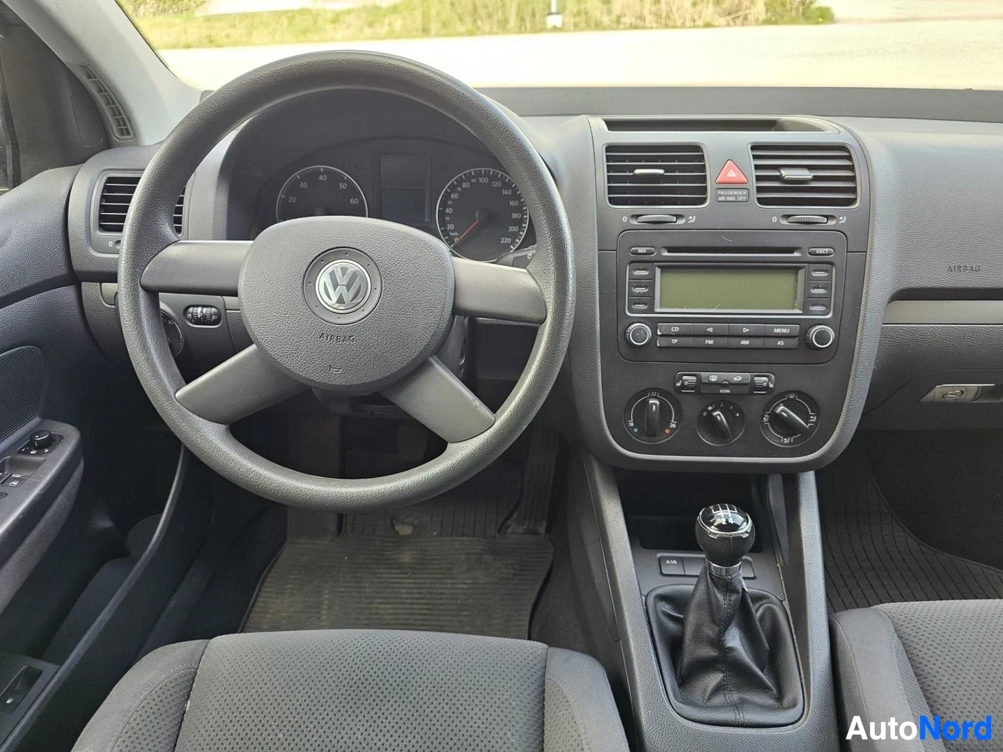 Etuistuimet: Ohjaustaulusta yläkatsaus, VW-ratti ilmaisin, nopeusmittari, radio näytöllä, ilmastoinnin ohjaimet, harmaa sisustus