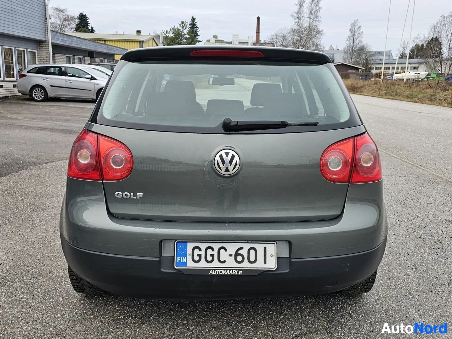 Takaa: Harmaa Volkswagen Golf takapielu suoraan takaa kuvattuna. Punaiset takavalot, Volkswagen-logo ja GOLF-merkintä näkyvissä. Rekisterikilpi