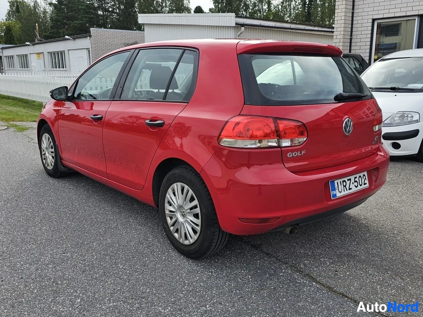 Takaviisto: Punainen Volkswagen Golf -hatchback takaa-viistosta oikealle, jossa näkyy koko takaosa ja oikea sivu. Rekisterinumero näkyy takalevyssä. Teksti 'GOLF' j