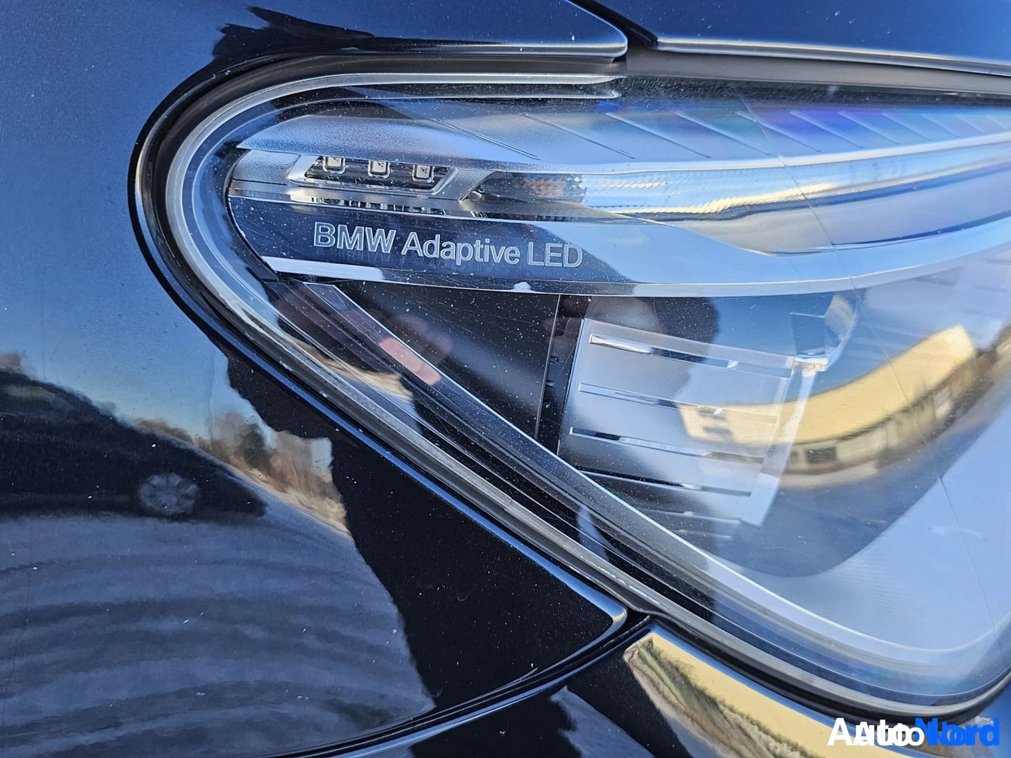 Yksityiskohta: Lähikuva auton ajovalosta, jossa näkyy teksti "BMW Adaptive LED".