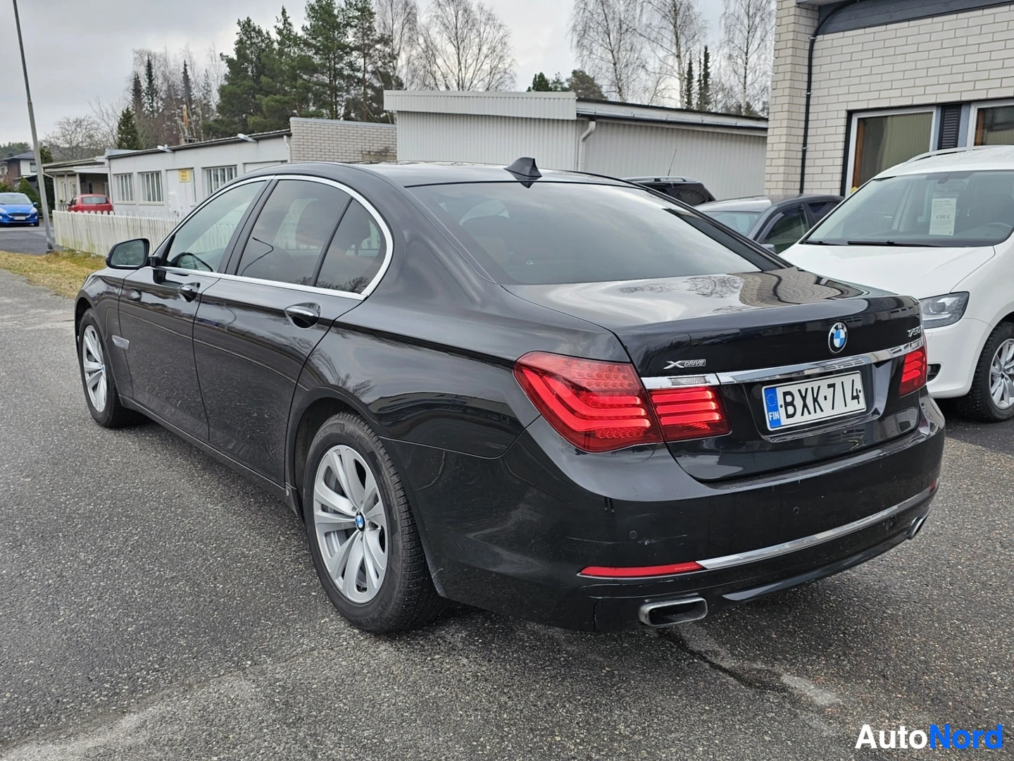 Takaviisto: Musta BMW-sedan kuvattuna kolmen neljänneksen kulmasta oikealta, näkyvät etupuskuri, oikea sivu ja takavalosarja rekisteritunnuksella