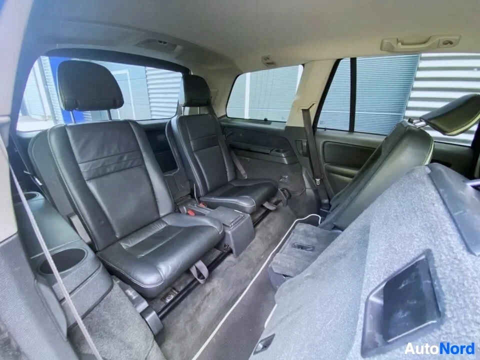 Takaistuimet: Auton takapenkin sisäänäkymä, mustat nahkaistuimet kahden istuja-asennon kanssa vasemmalla, harmaa istuin oikealla, isofix-kiinnikkeet näkyvät, panoraama-kattol