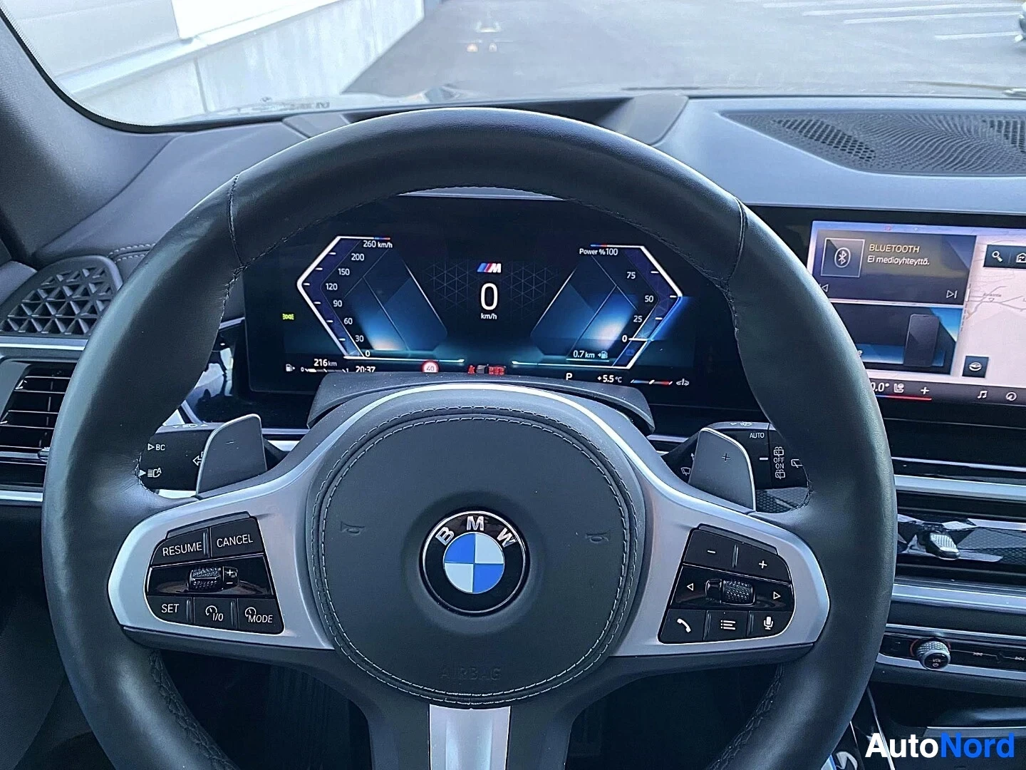 Ohjaamo: BMW-ohjauspyörä M-logolla, digitaalinen mittaristo näyttää 0 km/h ja 216 km ajon etäisyys, Bluetooth-kytkin oikealla infotainment-näytöllä