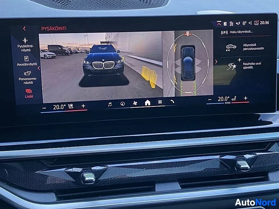 Yksityiskohta: Ajoneuvon panoraamakamera-näyttö näyttää mustasta BMW-autosta etunäkymää parkkipaikalla ja ylhäältä kuvaa. Näytössä näkyvät kellonaikaa 20:36.