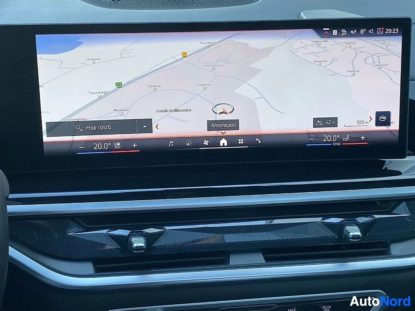 Yksityiskohta: Auton infotainment-näytön navigointikartta ja säätöpalkit, näytössä kartalla ajoneuvon sijainti ja ilman lämpötila 20,0 astetta