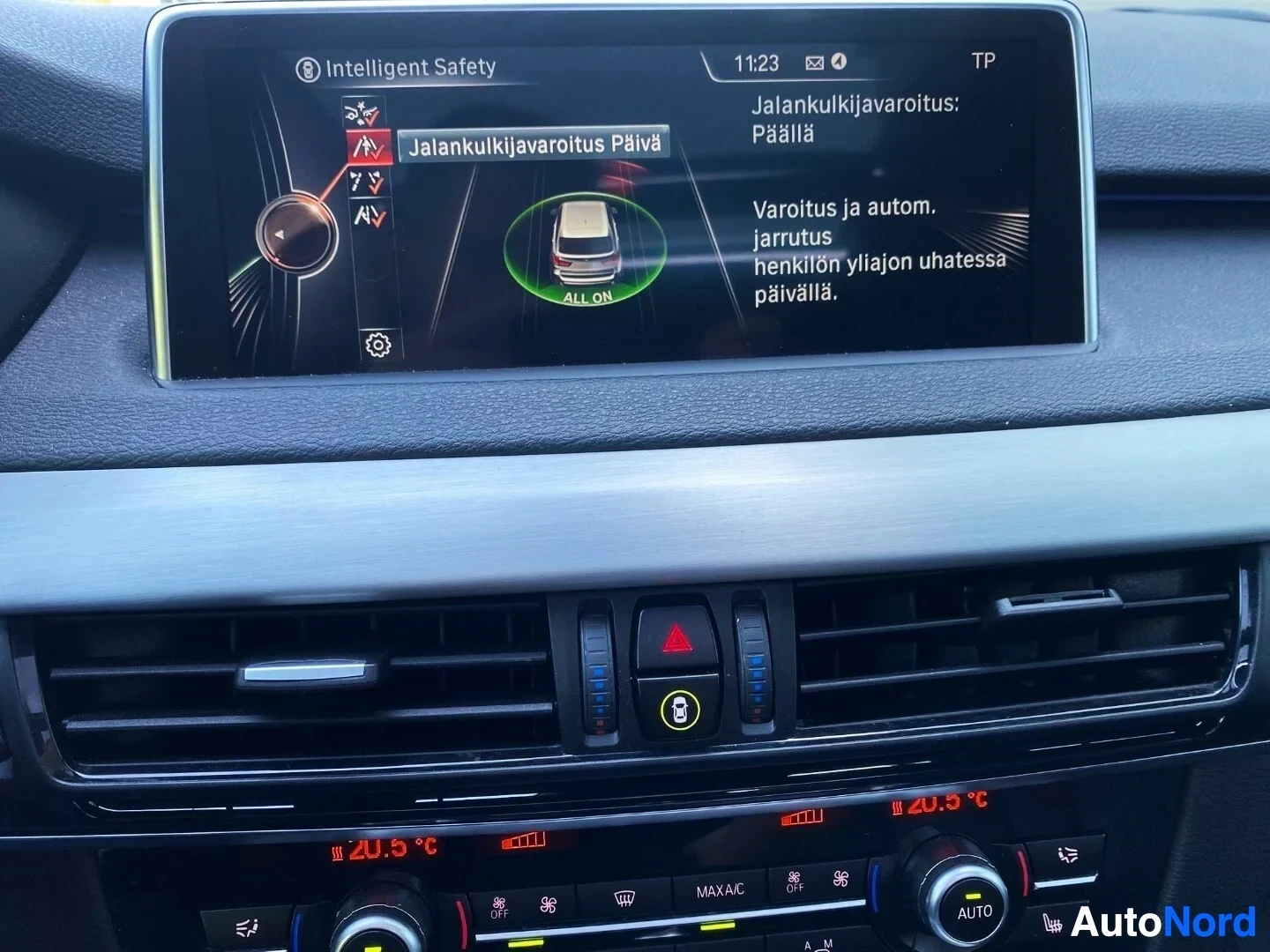 Yksityiskohta: BMW infotainment näyttö näyttää Intelligent Safety -varoitusjärjestelmää ja etäisyysvaroitusta, ilmastointi näyttää 20,9 °C, kellon aika 11:23