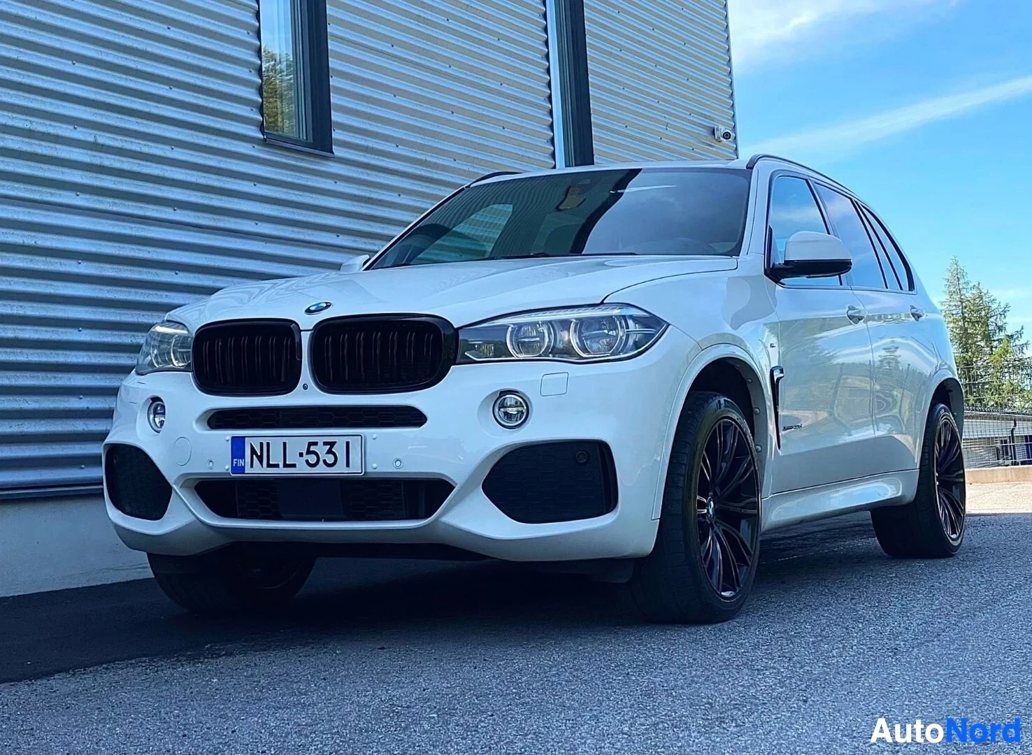 Etuviisto, nokka vasemmalle: Valkoinen BMW X5 SUV kuvattu kolmen neljänneksen kulmasta vasemmalta, etupuoli näkyvissä. Rekisterikilpi. Musta säleikkö, LED-ajovalot, mustat
