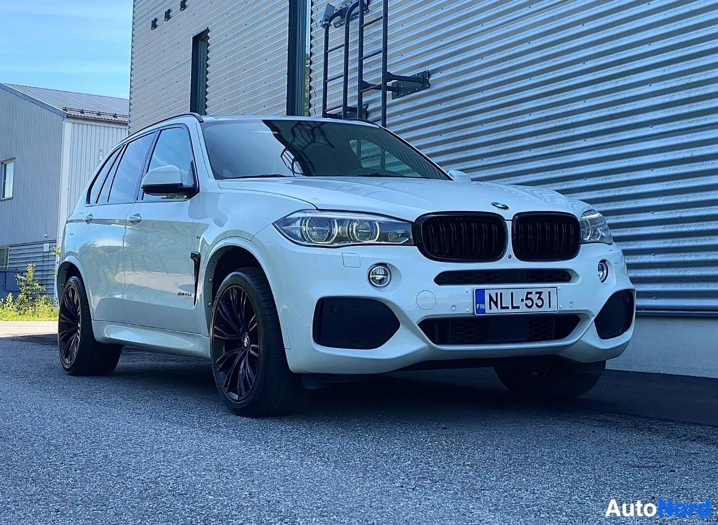 Etuviisto, nokka oikealle: Valkoinen BMW X5 SUV kuvattu kolmen neljänneksen kulmasta oikealta, etupuoli näkyvissä. Rekisterikilpi. Musta säleikkö, LED-ajovalot, mustat reng