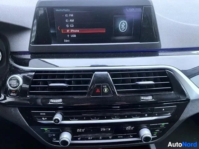 Ohjaamo: Auton keskikonsolin näyttö ja ilmastoinnin ohjaimet. Näytössä näkyvät FM, AM, CD, iPhone ja USB -valinnat sekä Bluetooth-kuvake. Alla ilmastoinnin säätöpainikke