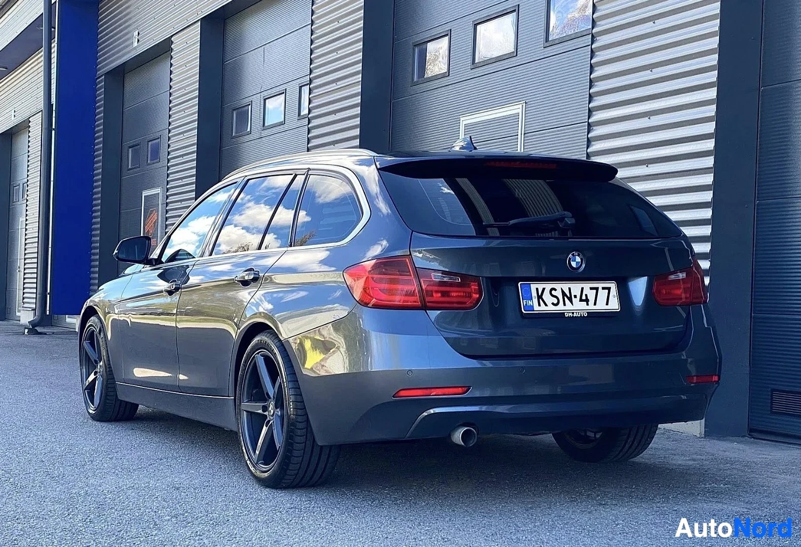 Takaviisto: Tummansininen BMW farmari kuvattuna takaa ja vasemmalta puolelta. Näkyvillä takaosa ja vasen sivu. Rekisterikilvessä teksti ja merkintä 'KSN-AUTO'. Pysä