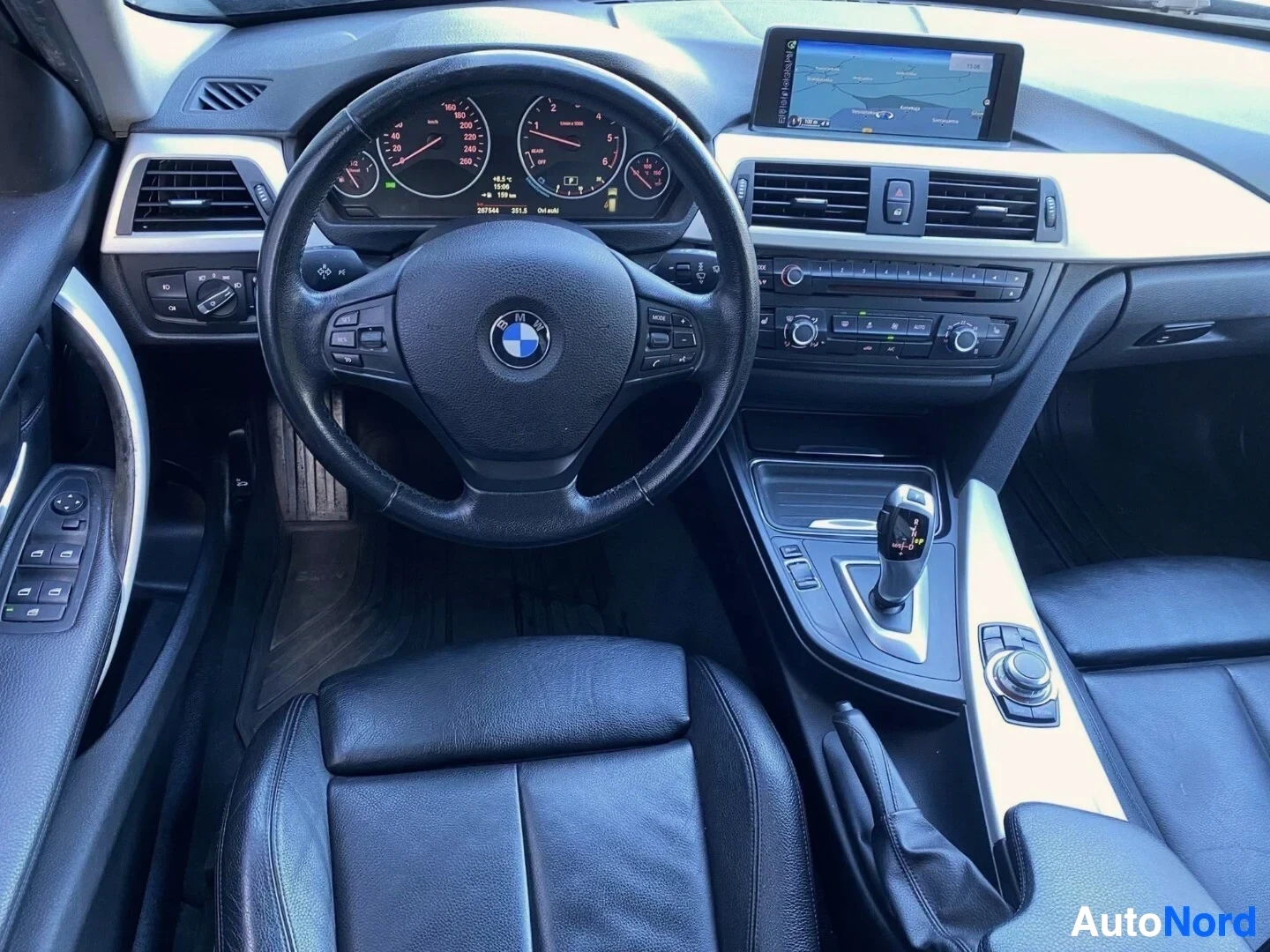 Etuistuimet: BMW 3-sarjan sisäkuva keskeltä. Näkyvissä BMW-logo ohjauspyörässä, analogiset mittarit, digitaalinen näyttö, nahkainen ohjauspyörä ja manuaalinen vaihteisto.