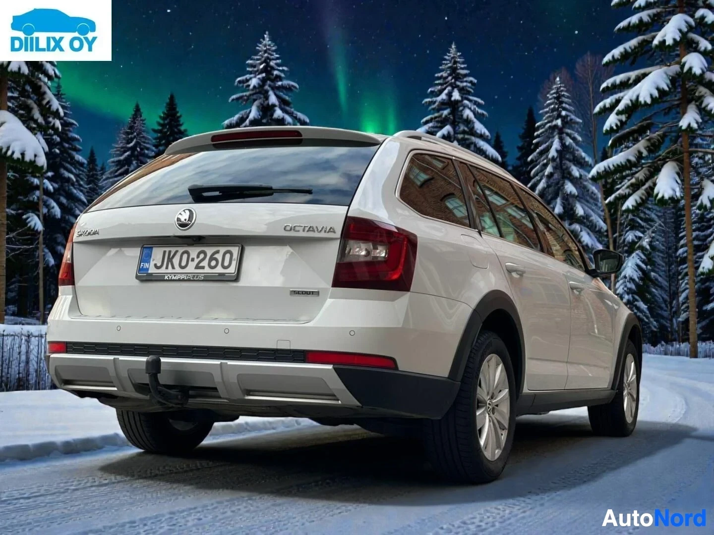 Takaviisto: Valkoinen Skoda Octavia maastoauto sivusta, lumisella alueella havumetsinä taustalla, rekisterikilvessä JK0:260