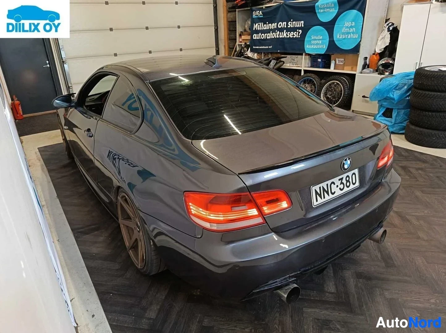 Takaa: Musta BMW-coupe takaosasta lähempää kuvattuna varikkohallin sisätiloissa. Punaiset LED-takavalo, ahtoputki näkyy. Rekisterikilpi