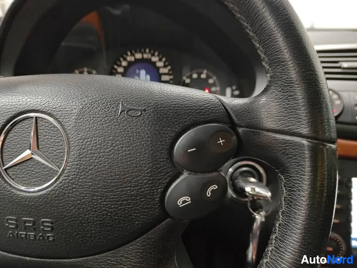 Yksityiskohta: Mercedes-Benz ohjauspyörä SRS-ilmatyynyin merkinnöillä ja puhelimen sekä äänensäädön painikkeet
