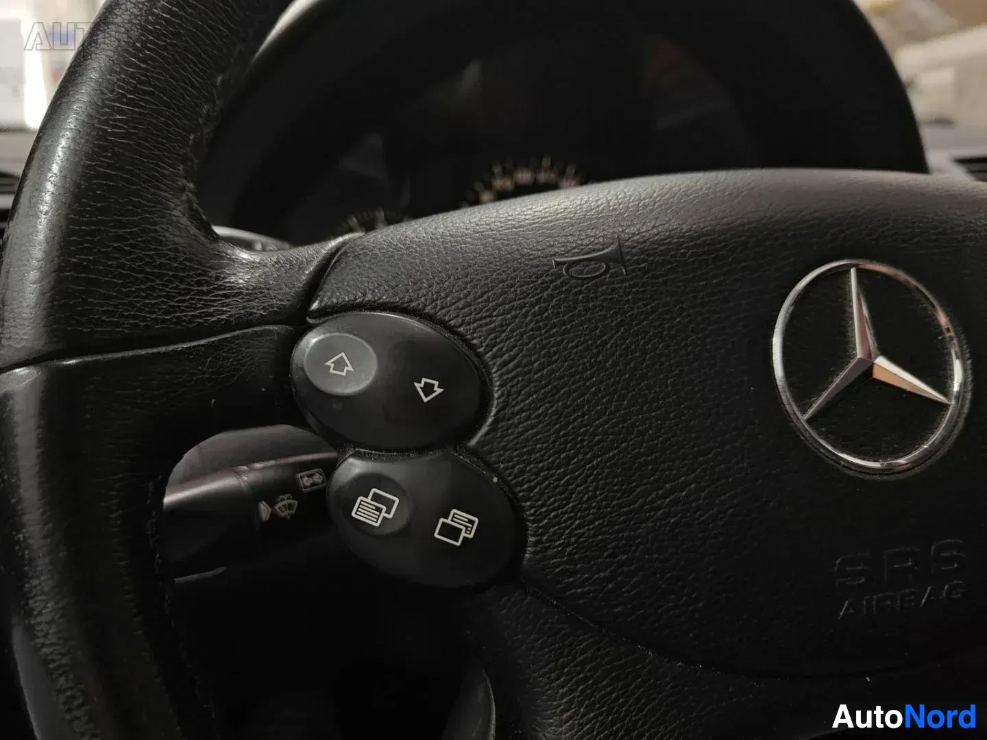 Yksityiskohta: Mercedes-Benz ohjauspyörä monella funktiolla ja SRS-ilmatyynyin merkinnöillä sekä painikkeet auton toiminnoille