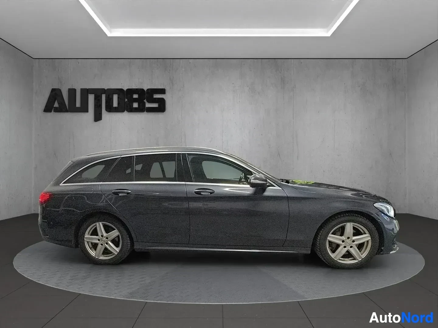 Sivulta: Mercedes-Benz estate, harmaa väri, sivunäkymä oikealle, valkoisen katon showroomissa