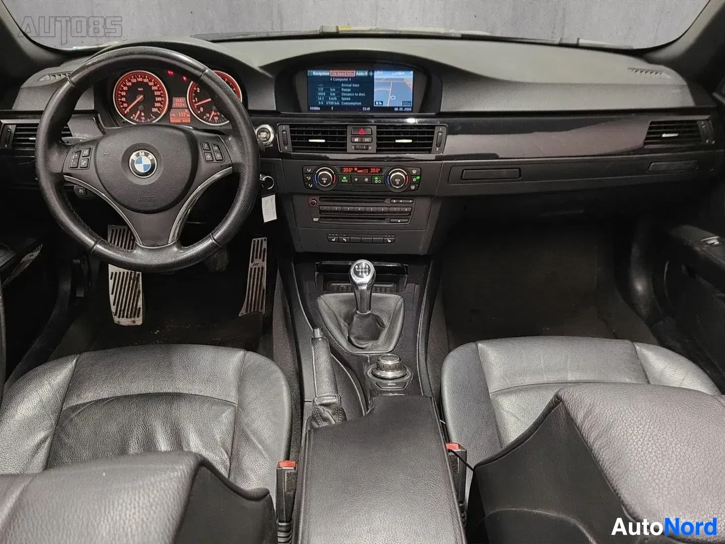 Etuistuimet: Kuljettajan paikka kokonaisuudessaan näkymä, BMW ohjauspyörä, punaiset mittarit, näyttö navigoinnilla, harmaa sisusta, kaksi penkkiä edessä