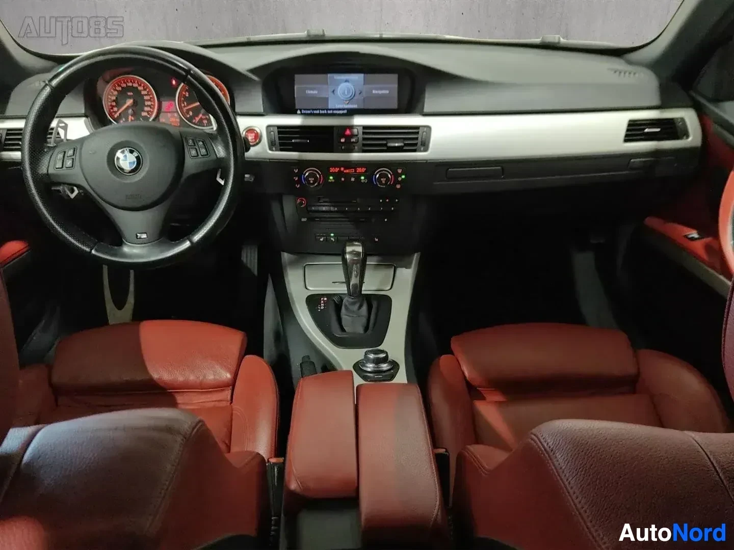 Ohjaamo: Sisätilakuva: ohjauspyörä BMW-logolla, punainen nahkaverhoilu, valkoinen dashboard, digitaalinen näyttö, kolme pääntukea näkyvissä etusijalla