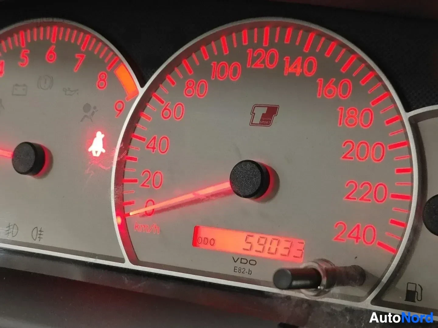 Yksityiskohta: Mittariston lähikuva, nopeusmittari ja moottorituntien mittari, lukema 59933 km, VDO E82-b merkintä