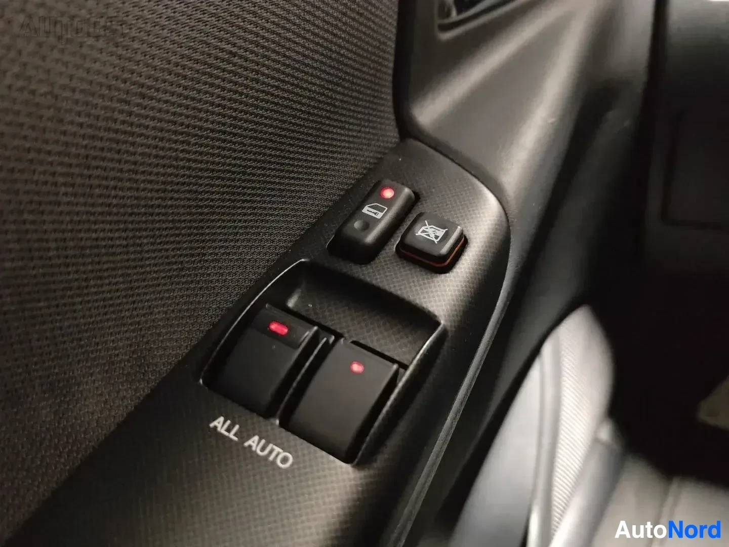 Yksityiskohta: Ohjauspyörän oikealla puolella olevat ikkunanopeuksien säätöpainikkeet ja ALL AUTO -merkintä alhaalla.
