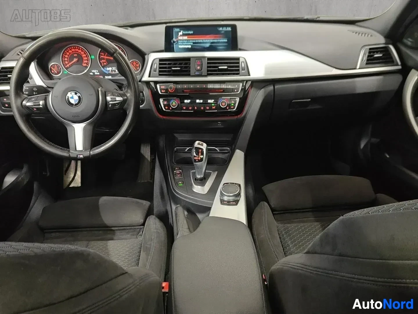 Ohjaamo: BMW 330 -auton ohjaamosta edestä kuvattu kuva. Näkyvissä ovat mustat istuimet, valkoinen kojelauta, digitaalinen näyttö, punaisen ja mustan värisillä numeroilla