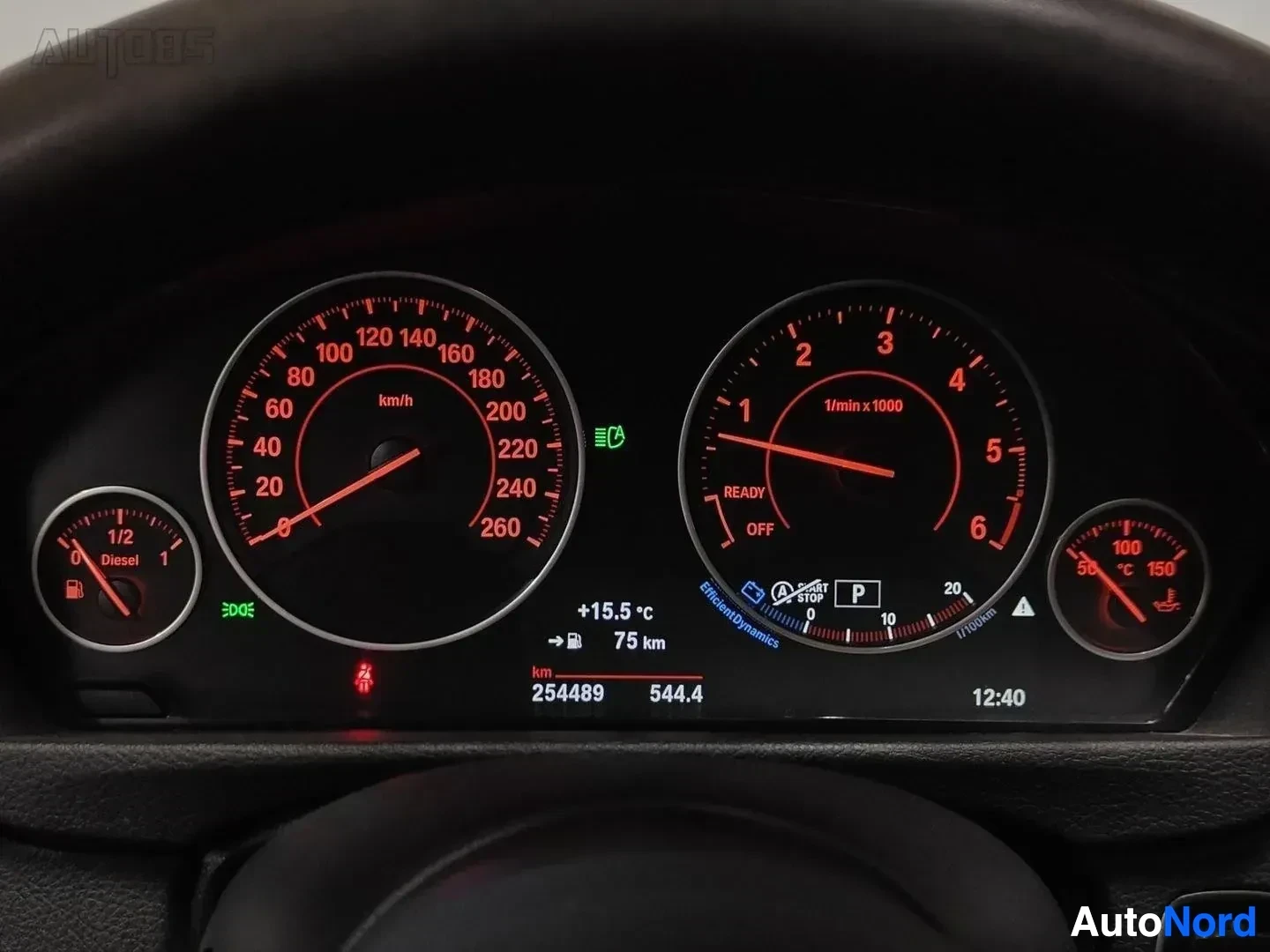 Yksityiskohta: BMW 330 -auton mittariston lähikuva, joka näyttää ajon tilastoja. Nopeudenmittari näyttää noin 20 km/h, kierroslukumittari on melkein tyhjä. Alla näkyy km-lukem