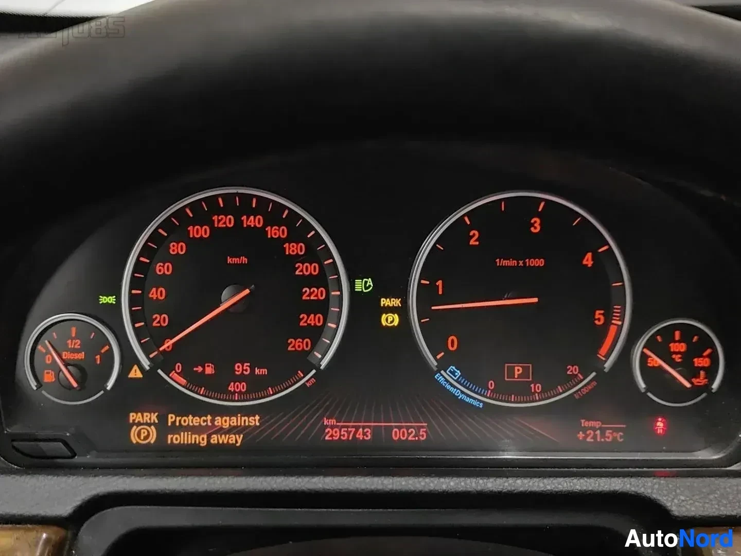 Yksityiskohta: Mittaristo oranssein numeroin. Nopeusmittari näyttää noin 40 km/h, kierrosluvun mittari noin 1000 r/min. Mittaristossa näkyy 295743 km ajettu.