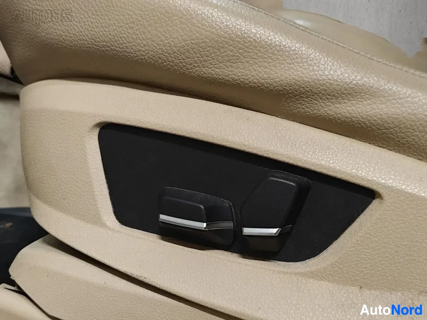 Yksityiskohta: Nahkaverhoiltu auton ovi, beige/kremivärinen nahka ylhäällä ja vaaleampi alapuolella, mustan värin ovenkäsittelijä ja säätöjohtimet