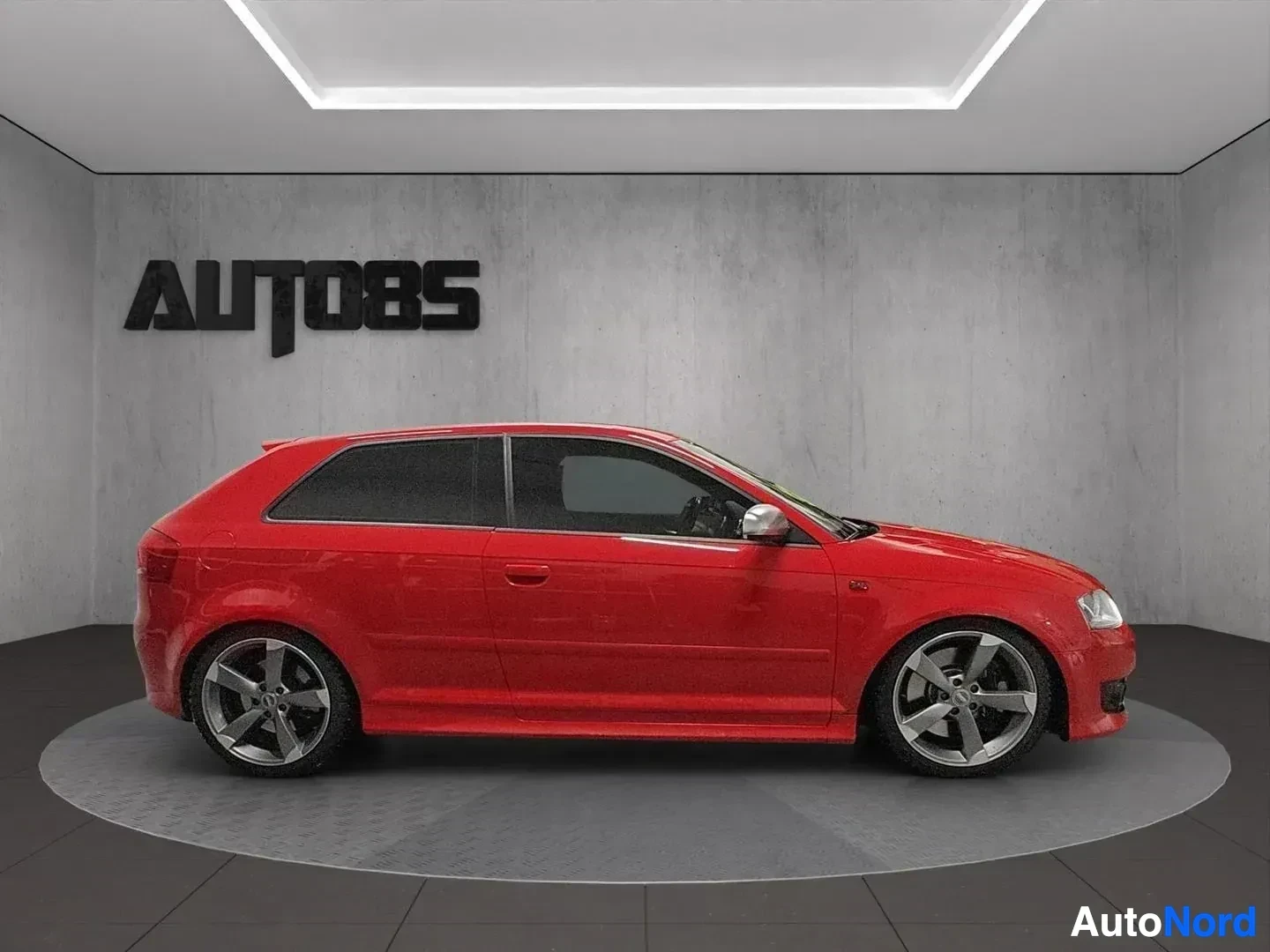 Sivulta: Punainen Audi-auto näkyy vasemmalta sivulta studiossa.