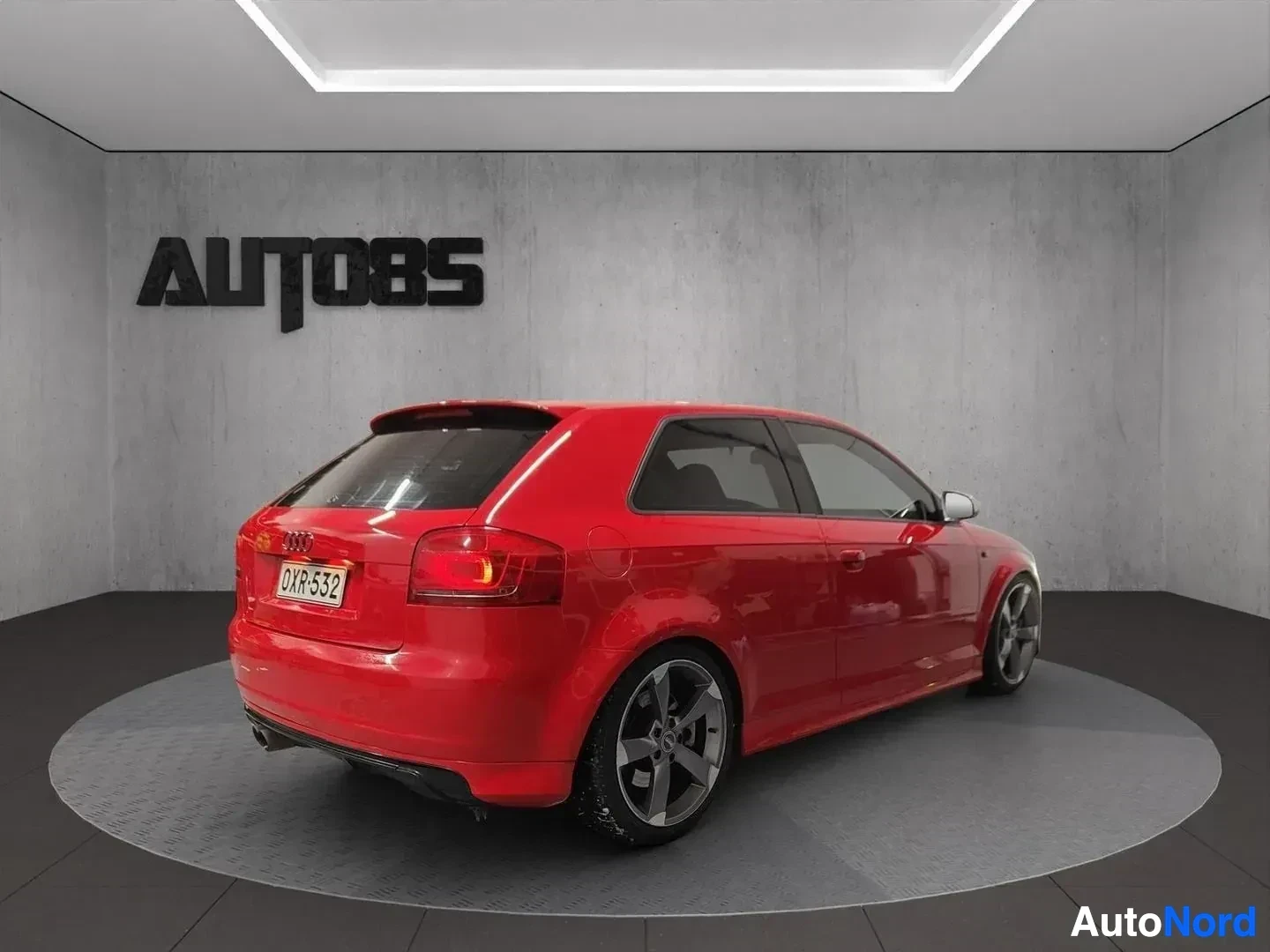 Takaviisto: Punainen Audi-auto näkyy takaa ja sivulta studiossa.
