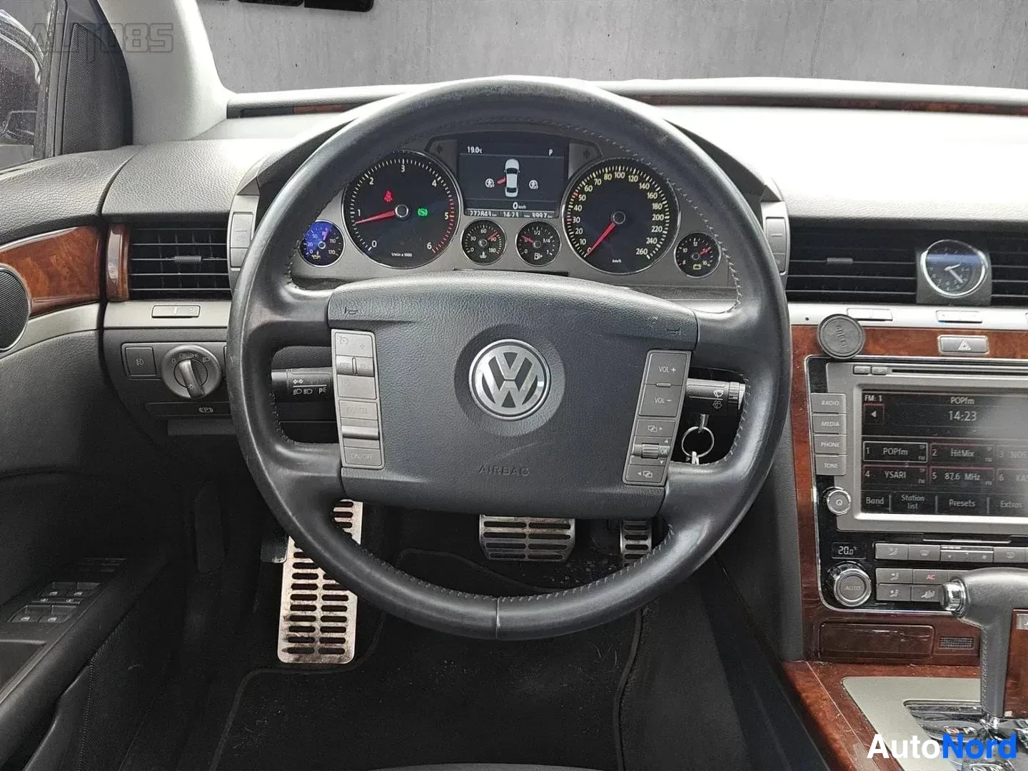 Yksityiskohta: Ohjausratti lähikuvassa, Volkswagen-logo, värimäärä tiedot ohjausohjauskeskuksessa, pieni sininen näyttö, ruskea verhoilu oikealla