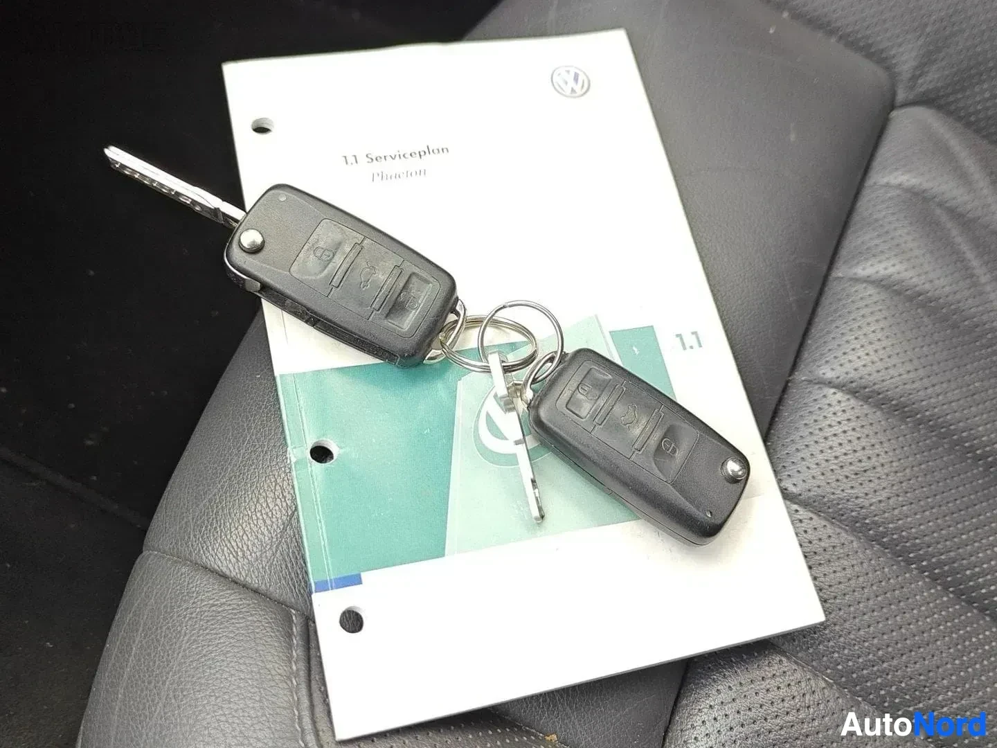 Asiakirja: Kaksi avaimenperää sekä Volkswagen Serviceplan-asiakirja, turkoosi sivuilla ja VW-tunnus