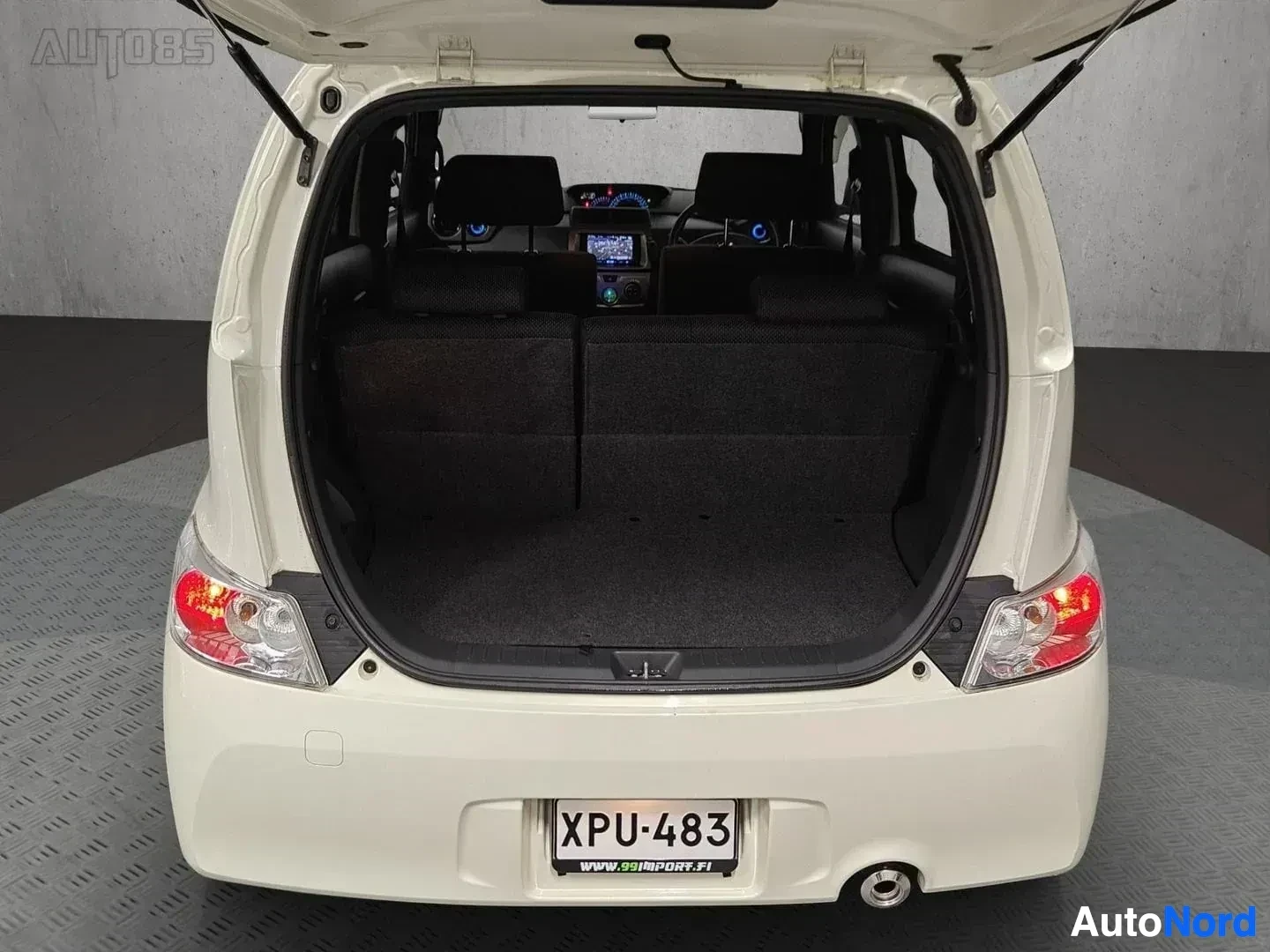 Tavaratila: Valkoinen auto takakontin avoin näkymä, musta sisäpuoli ja tummat istuimet näkyvillä, rekisteritunnus