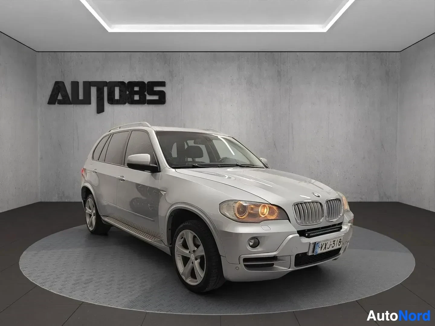 Etuviisto, nokka oikealle: Valkoinen BMW X5 -maasturi kuvattuna oikeasta etukolmelle osoittavassa kulmassa sisätiloissa.