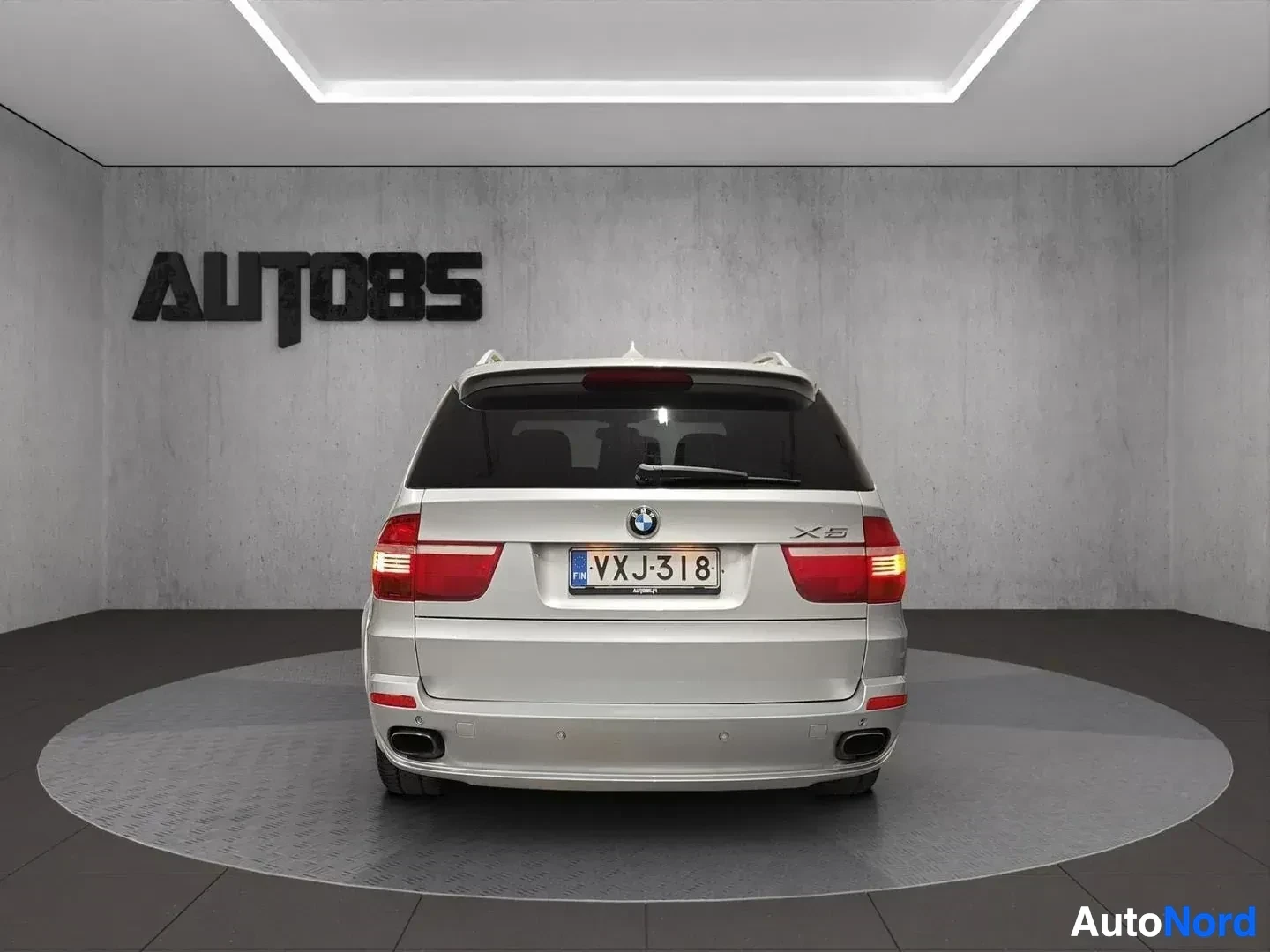 Takaa: Hopeanvärinen BMW X5 -maastoauto takaa kuvattuna. BMW-tunnus ja X5-merkintä näkyvät selvästi. Rekisterikilpi näkyy