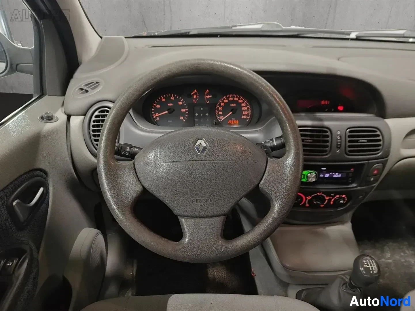Yksityiskohta: Lähikuva ohjausrenkaasta ja instrumenttipaneelistä: Renault-tunnus, nopeusmittari ja kierroslukumittari punaisen värin sätein, näyttö keskellä vihreällä tekstil