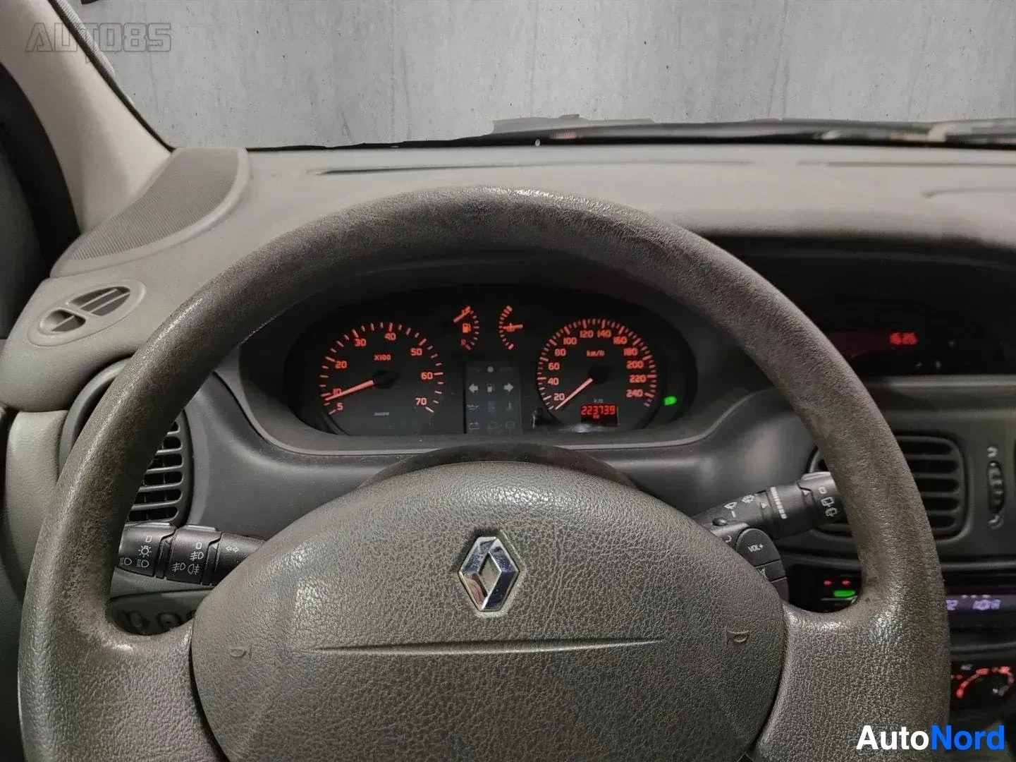 Yksityiskohta: Lähikuva ohjausrenkaasta ja instrumenttipaneelistä: Renault-tunnus, nopeusmittari ja kierroslukumittari punaisen värin sätein, keskellä näyttö