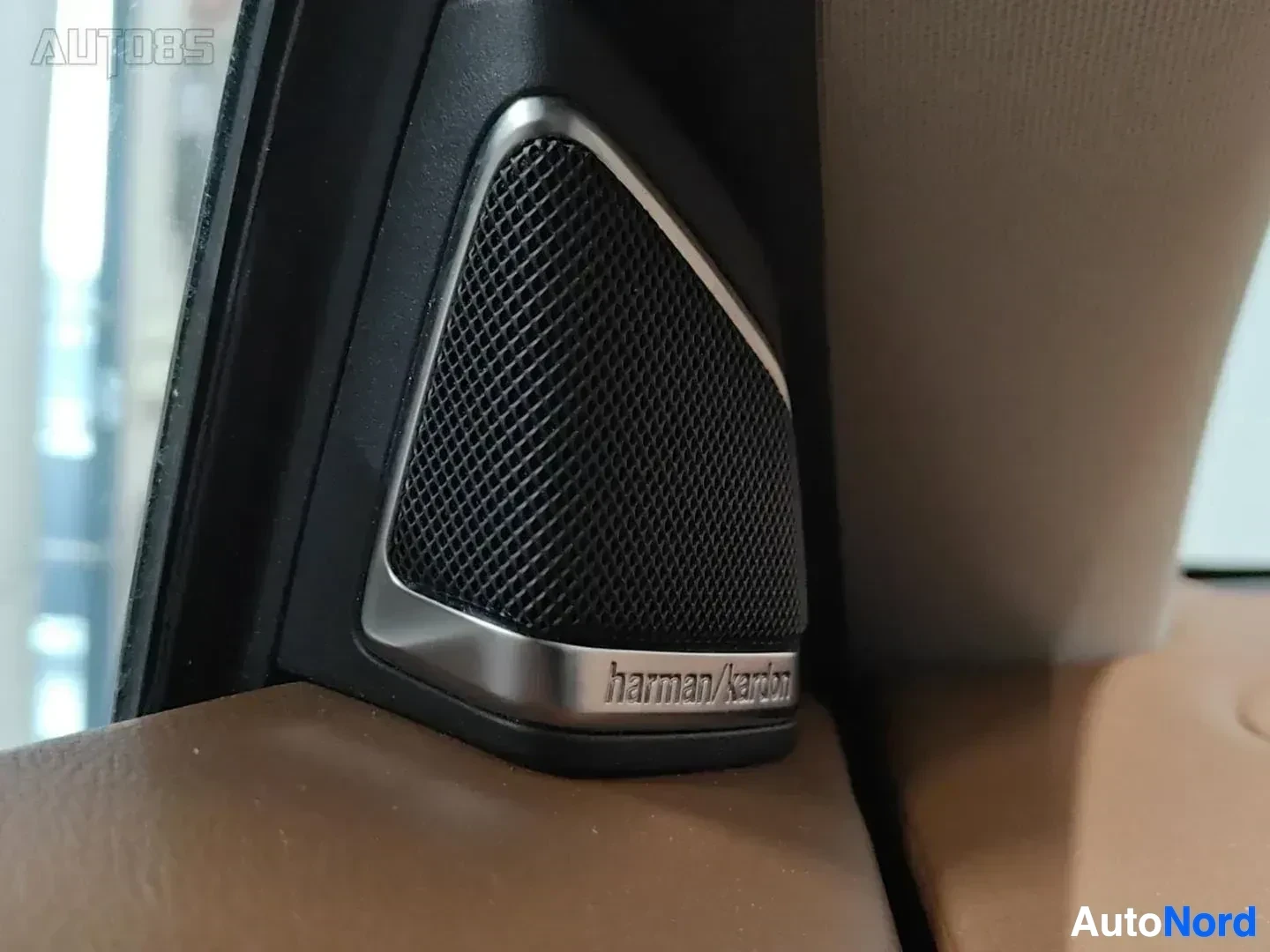 Yksityiskohta: Sisäkaton kaiutin Harman/Kardon-merkinnällä, mustaväriset kaiutinelementit ja metalliviimeistelyä sisältävä sisustusdetalji
