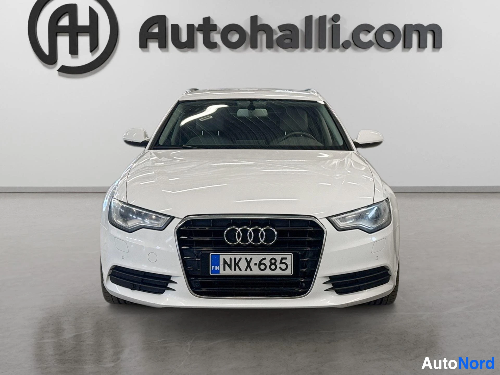 Valkoinen Audi A6 Avant edestä kuvattuna, Audi-merkki ja rekisterikilpi näkyvissä