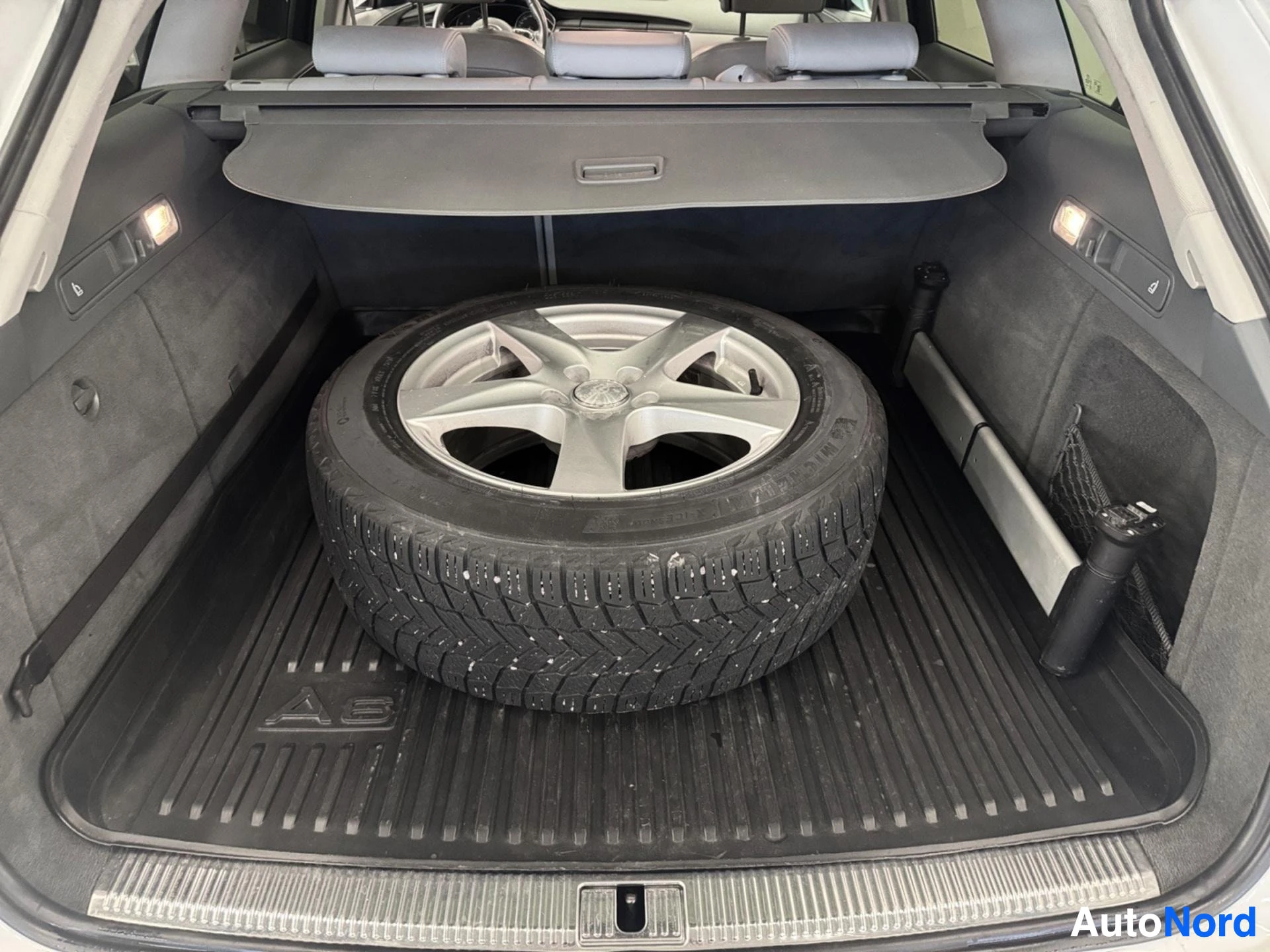 Trunk interior with spare tire, rubber mat, and storage compartments visible