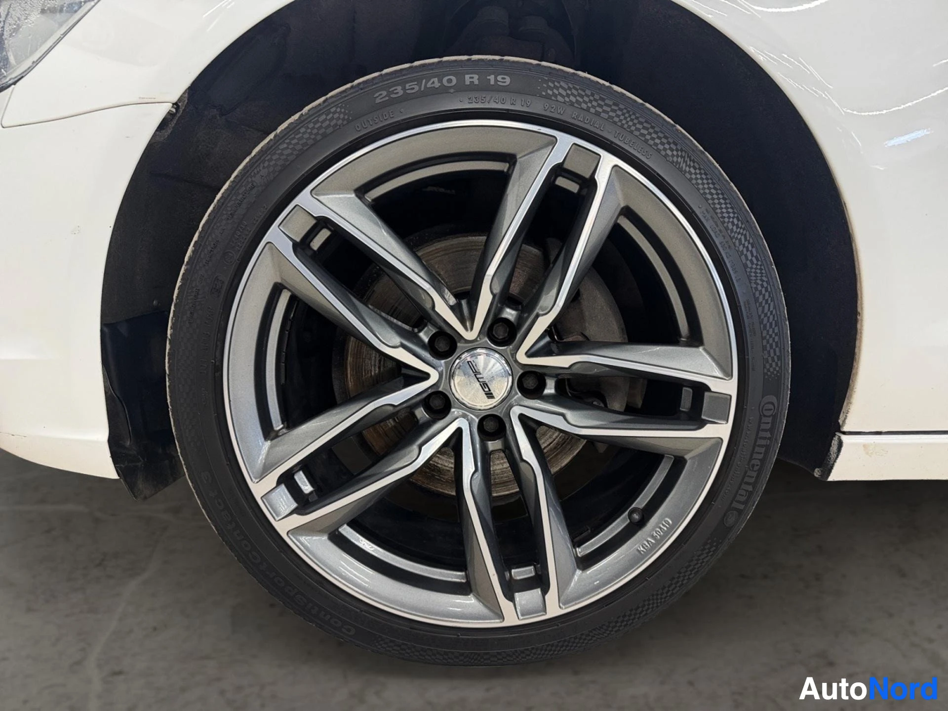 Alloy wheel with multi-spoke design and tire visible on white vehicle
