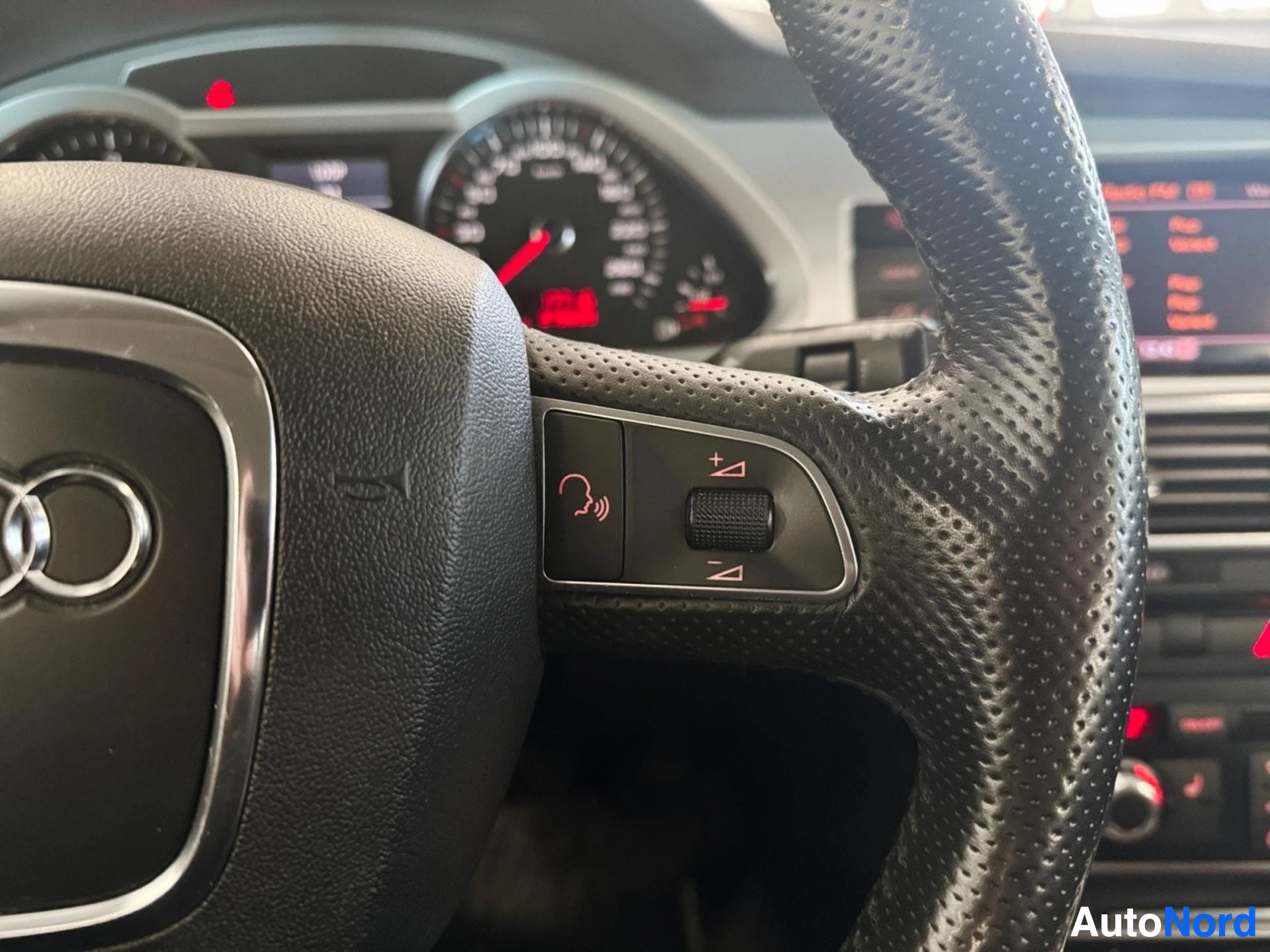 Steering wheel with phone and audio control buttons, dashboard with instrument cluster behind