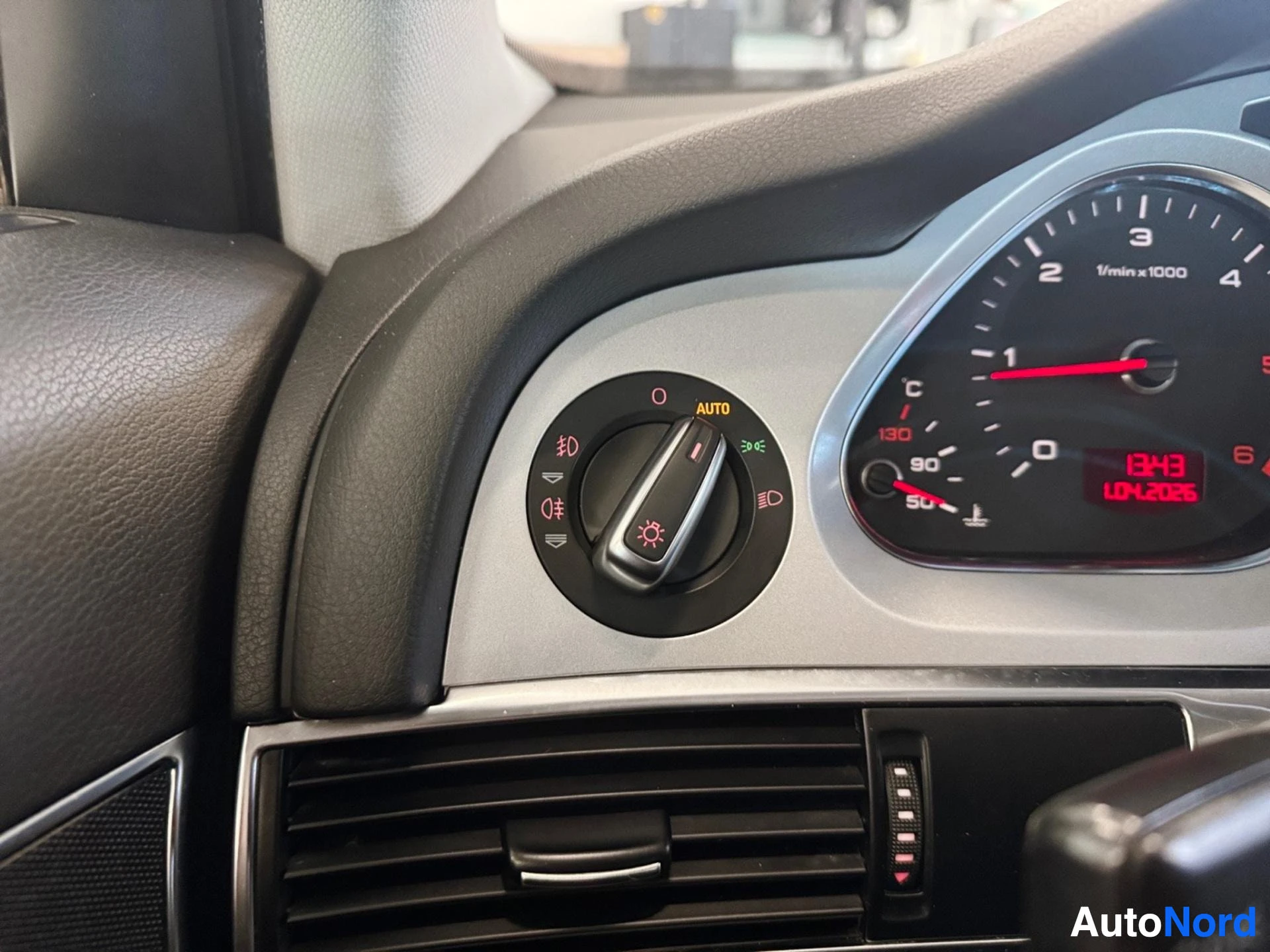 Driver dashboard area showing instruments, headlight controls, and air vents