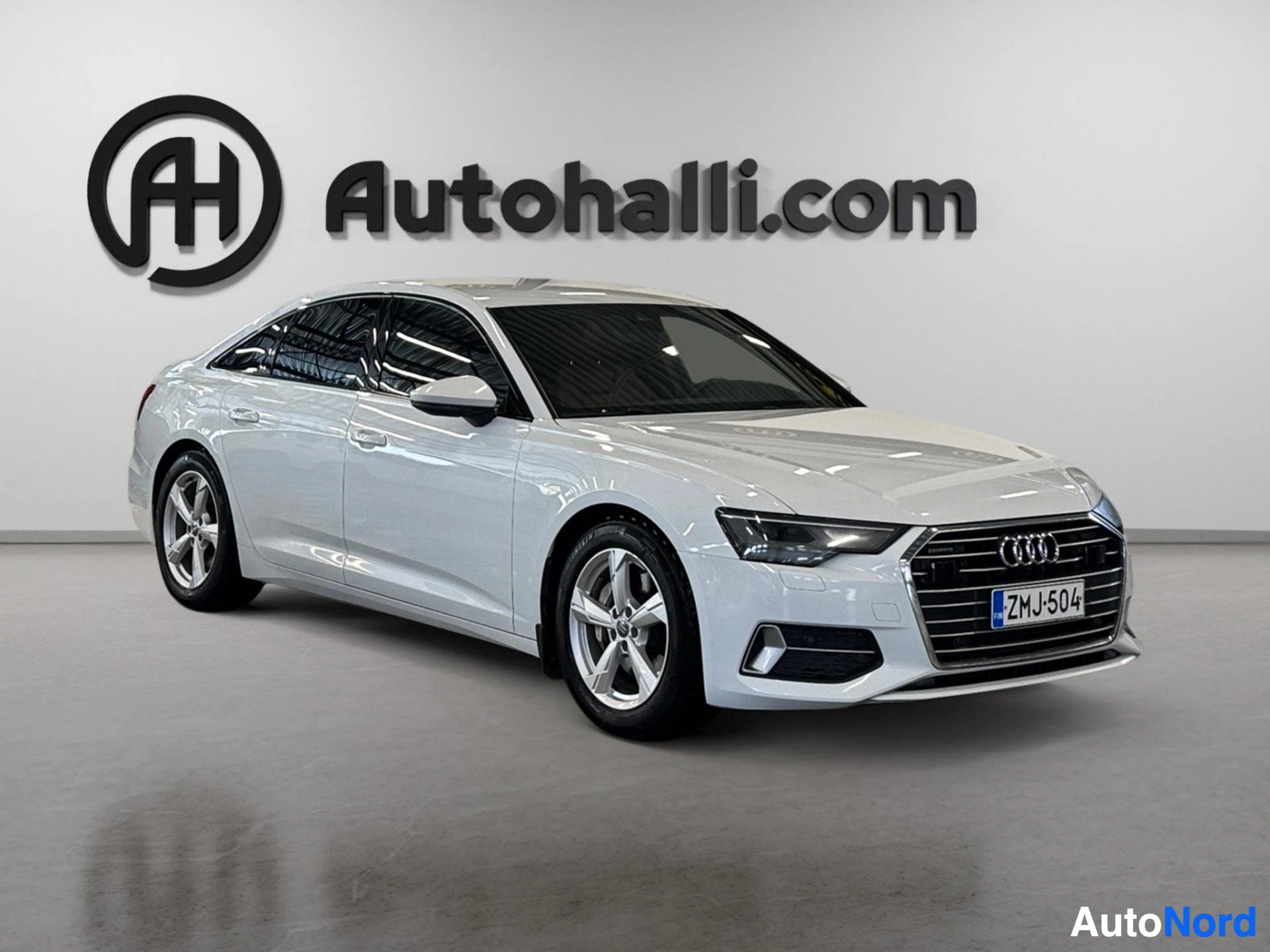 Valkoinen Audi A6 sedan kolmen neljäsosan sivukulmasta oikealta