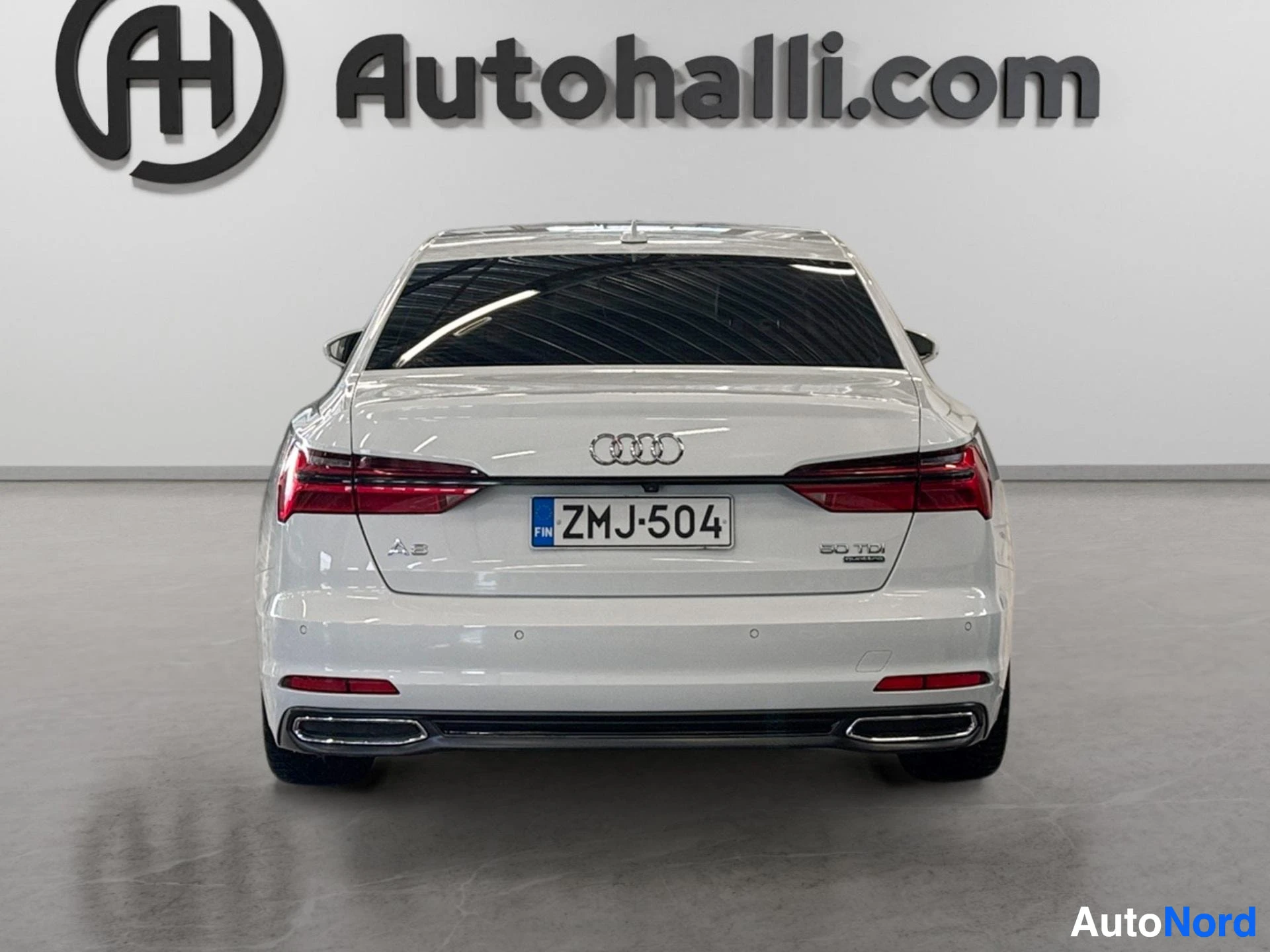 Valkoinen Audi A6 sedan suoraan edestä takaa kuvattuna