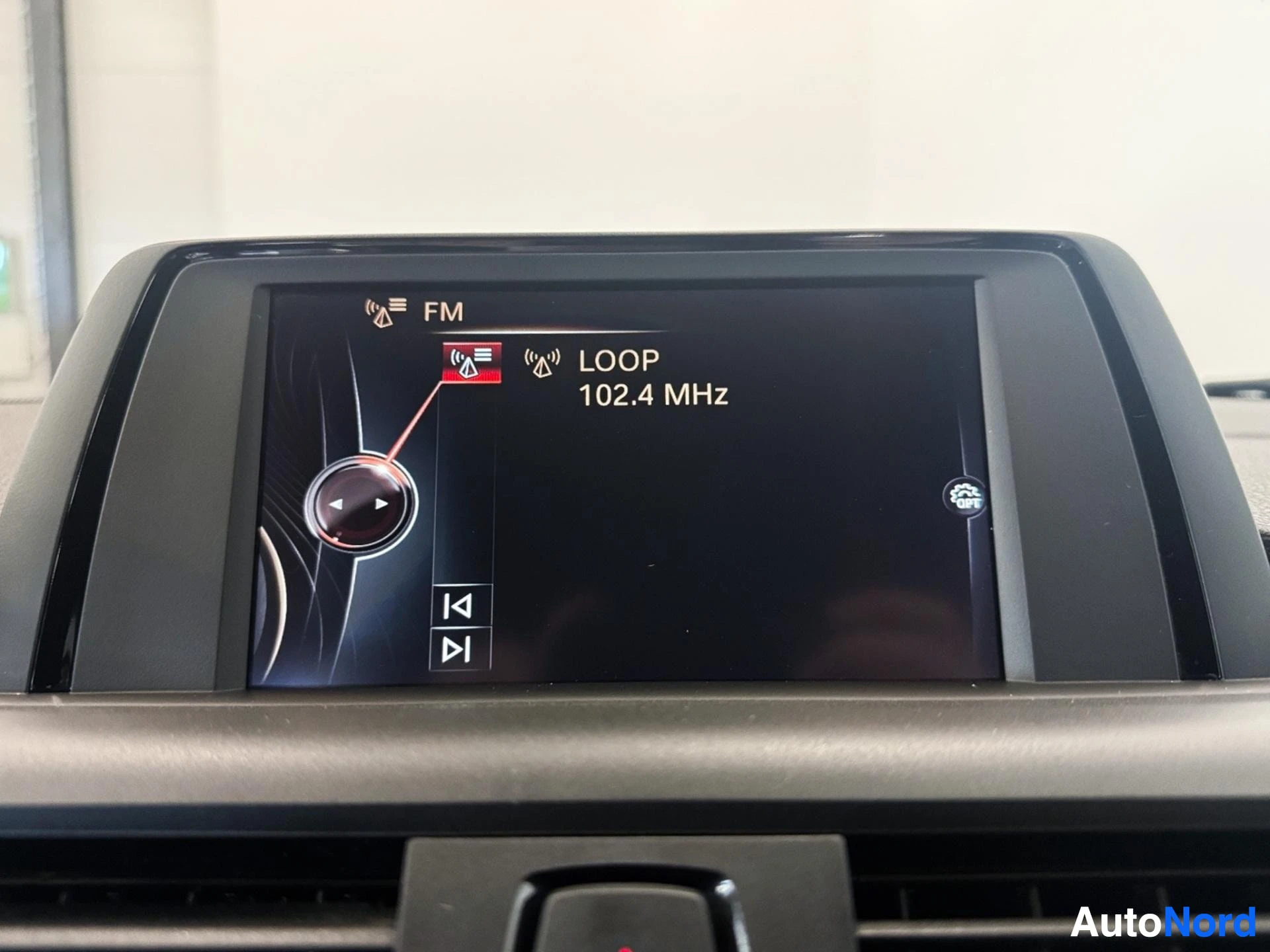 Dashboard infotainment display screen showing FM radio tuned to 102.4 MHz
