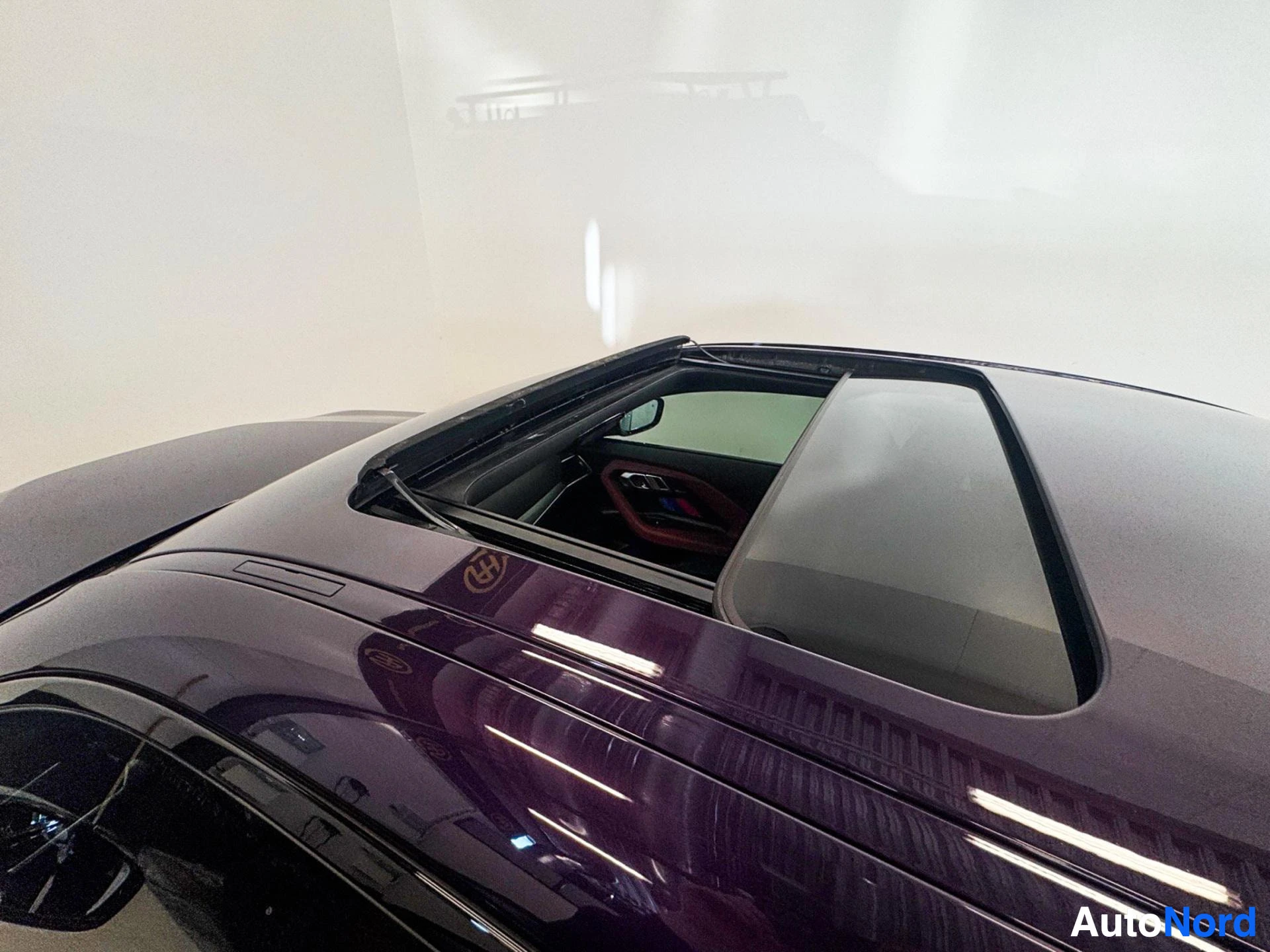 Coupe side profile with burgundy paintwork and open roof.