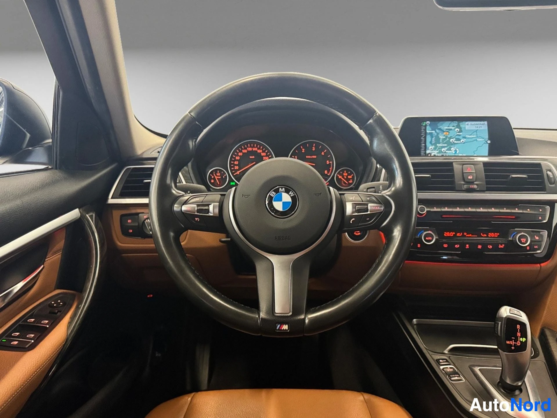 Ohjamo, BMW-ohjauspyörä, punainen mittaristo ja kosketuspaneeli näkyvissä.